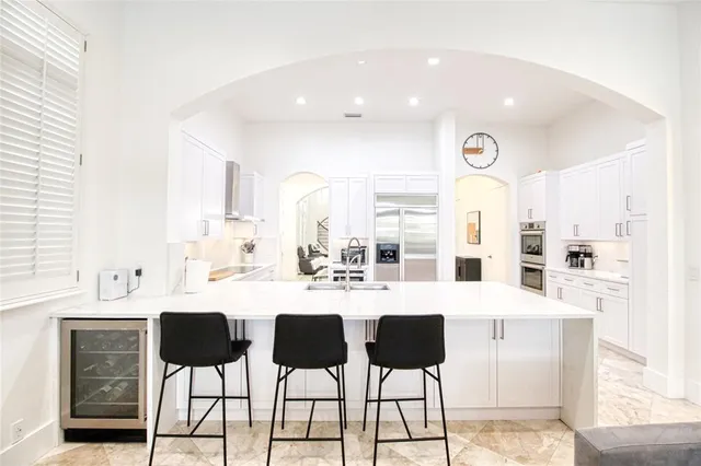 a living room with furniture a chandelier and kitchen view