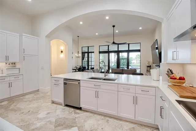 a large white kitchen with stainless steel appliances granite countertop a sink and dishwasher a stove with white cabinets