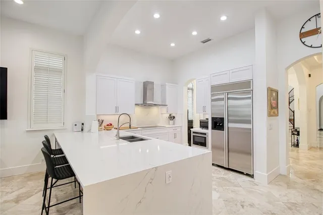 a large white kitchen with a sink and large stove top oven