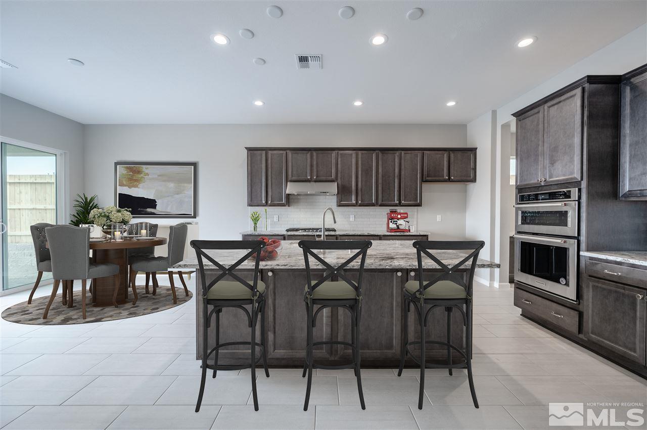 3035 Country Wind Lane, Unit HOMESITE 72 Reno, NV 89521 - Photo 3 of 15 a kitchen with stainless steel appliances kitchen island granite countertop a table chairs microwave and sink