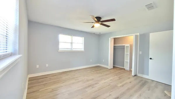 a view of empty room with wooden floor and fan