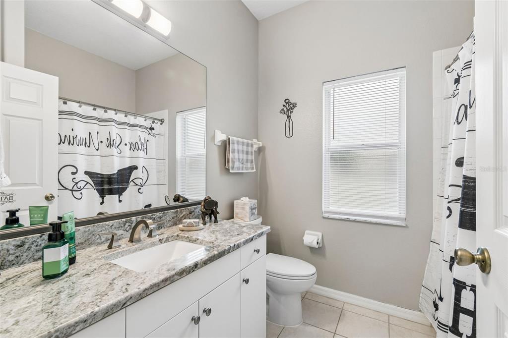 2006 Meadow Rue Court Trinity, FL 34655 - Photo 20 of 96 a bathroom with a granite countertop sink a mirror a vanity and a shower