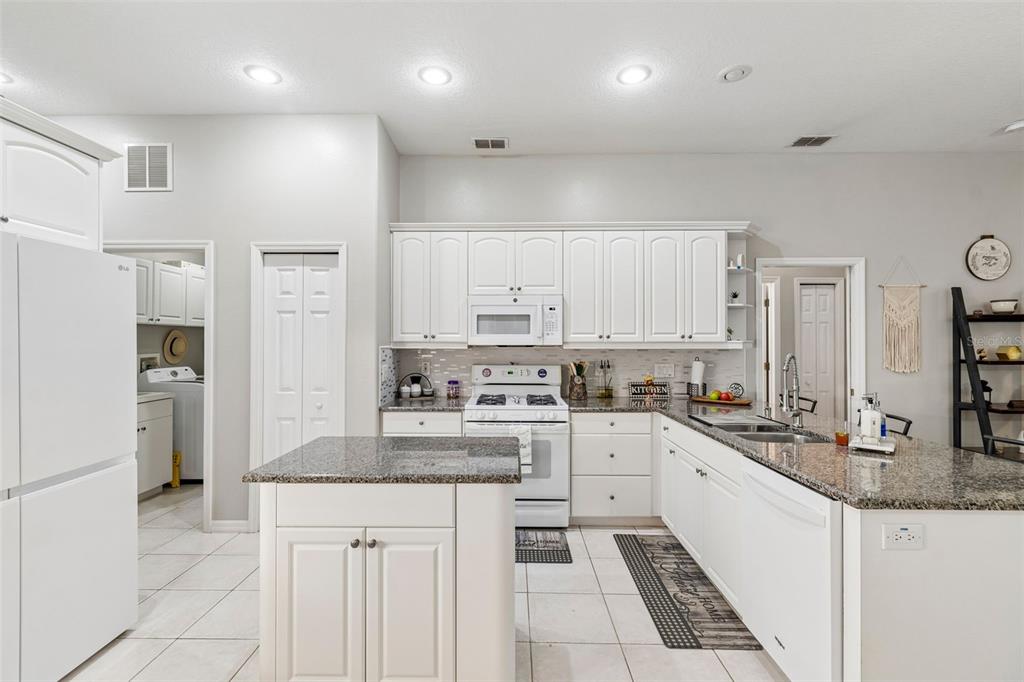 2006 Meadow Rue Court Trinity, FL 34655 - Photo 56 of 96 a kitchen with stainless steel appliances granite countertop a stove top oven a sink a refrigerator and white cabinets