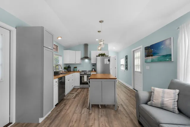 a kitchen with a refrigerator a stove top oven a sink dishwasher and white cabinets with wooden floor