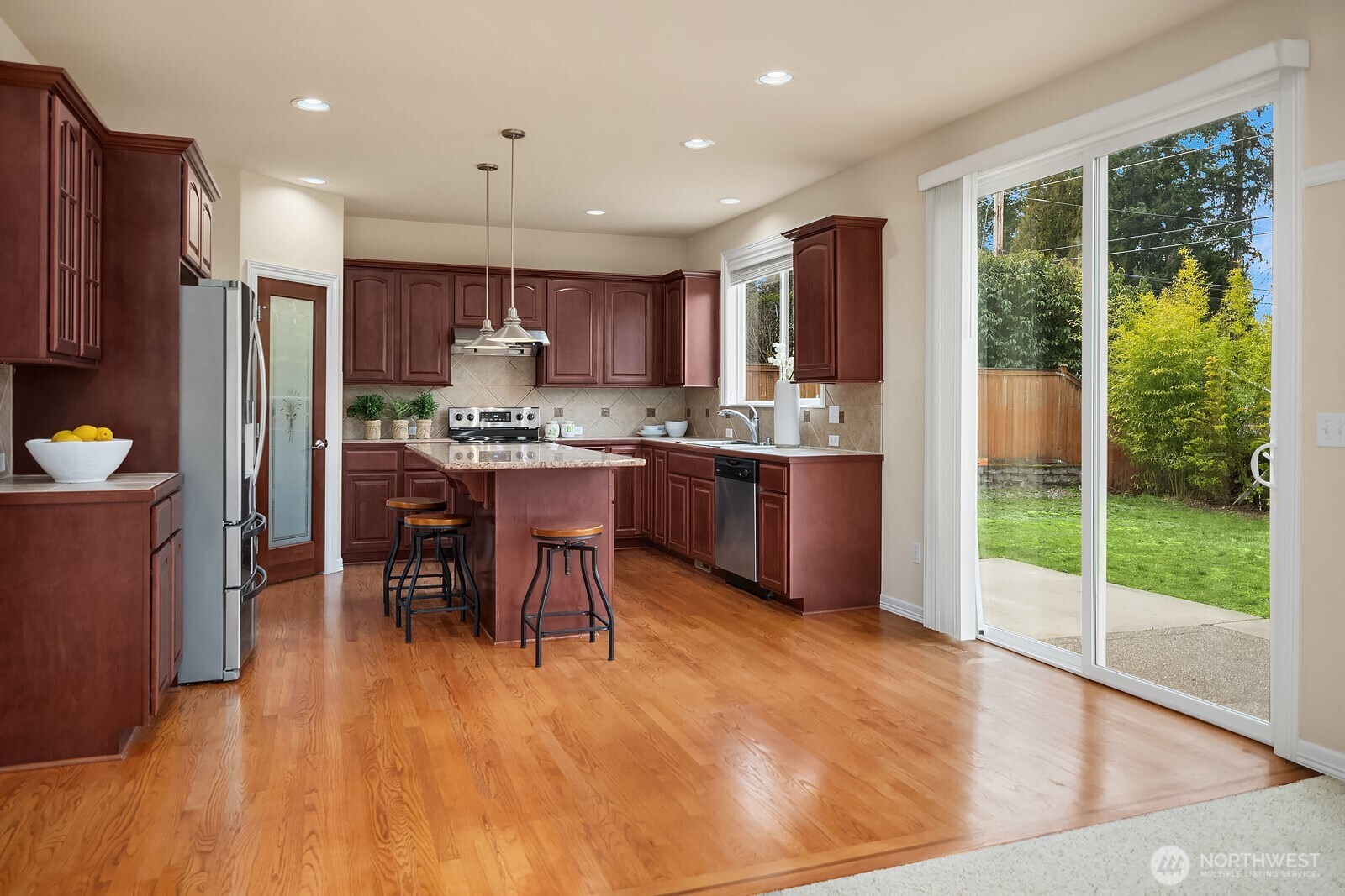5504 Northeast 13th Place Renton, WA 98059 - Photo 8 of 36 a kitchen with stainless steel appliances granite countertop a stove top oven a sink dishwasher a dining table and chairs with wooden floor