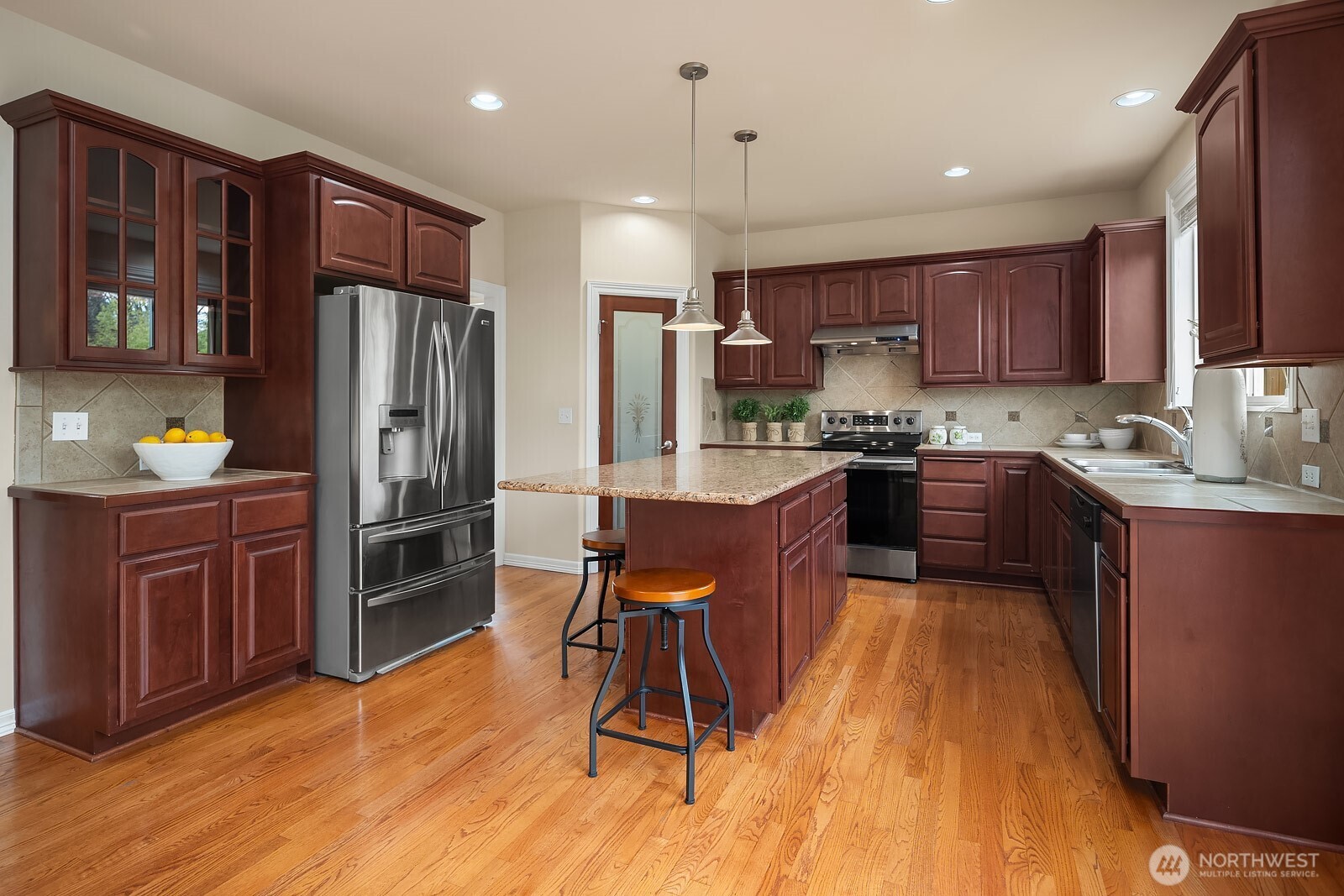 5504 Northeast 13th Place Renton, WA 98059 - Photo 10 of 36 a kitchen with kitchen island granite countertop wooden floors stainless steel appliances and cabinets