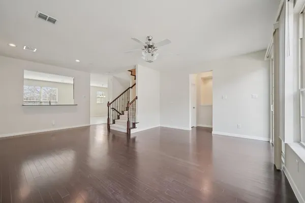 a view of an empty room with wooden floor and a ceiling fan