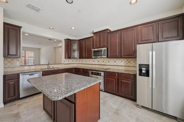 a kitchen with stainless steel appliances granite countertop a table chairs sink and refrigerator