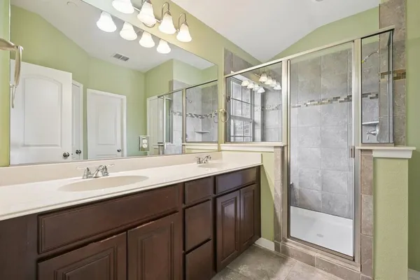 a bathroom with a double vanity sink mirror and shower