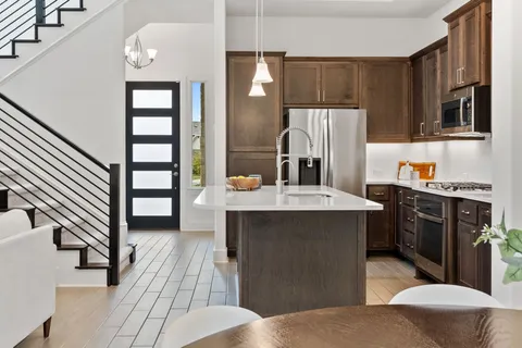 a kitchen with stainless steel appliances a sink dishwasher a refrigerator a stove and oven with wooden floor