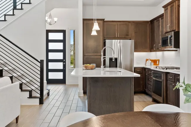 a kitchen with stainless steel appliances a sink dishwasher a refrigerator a stove and oven with wooden floor