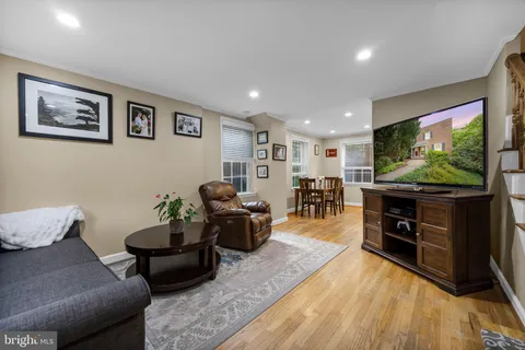 a kitchen with stainless steel appliances granite countertop a stove top oven a sink a dining table and chairs with wooden floor