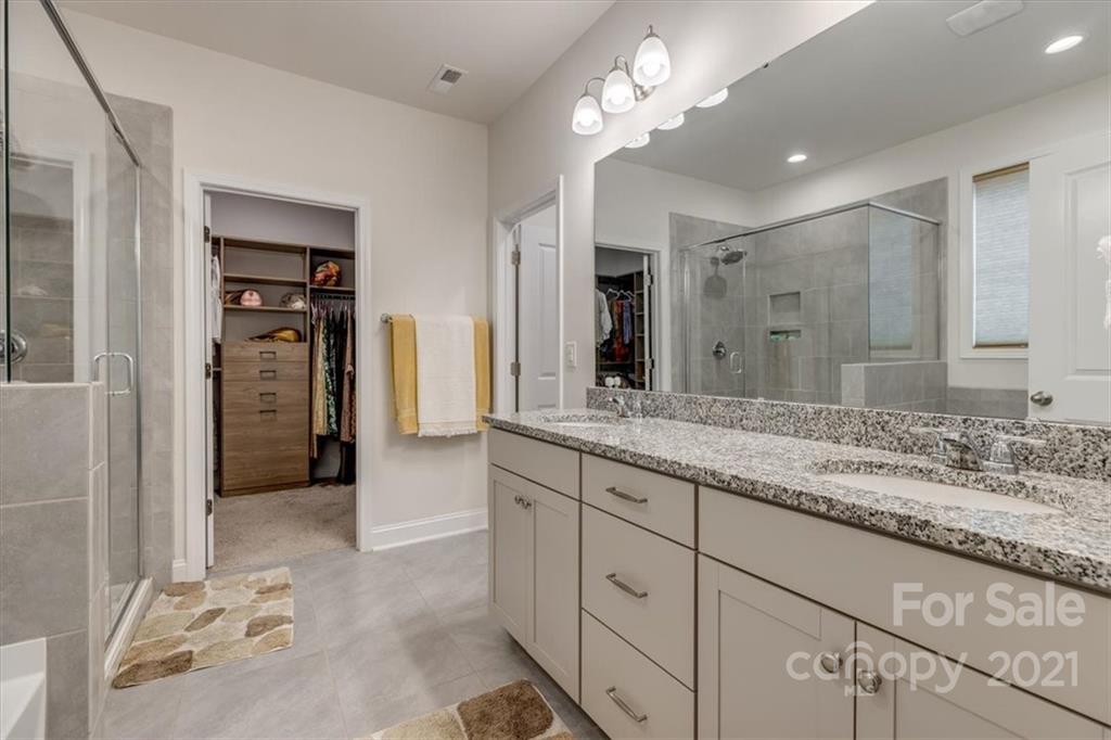 1007 Lydney Circle Waxhaw, NC 28173 - Photo 22 of 46 a bathroom with a granite countertop sink a mirror and a shower