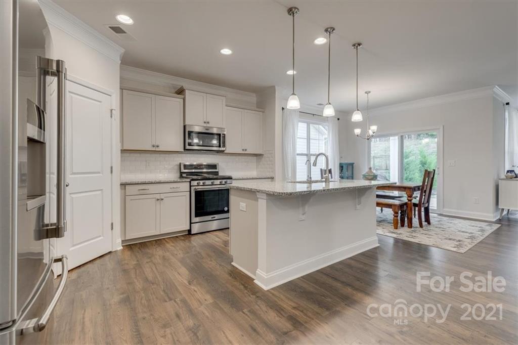 1007 Lydney Circle Waxhaw, NC 28173 - Photo 8 of 46 a kitchen with stainless steel appliances kitchen island granite countertop a stove a sink a center island a refrigerator and a wooden floor