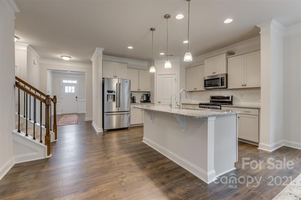 1007 Lydney Circle Waxhaw, NC 28173 - Photo 9 of 46 a kitchen with stainless steel appliances kitchen island granite countertop a stove a sink a refrigerator and white cabinets with wooden floor