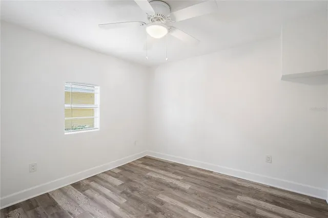 an empty room with a window and ceiling fan