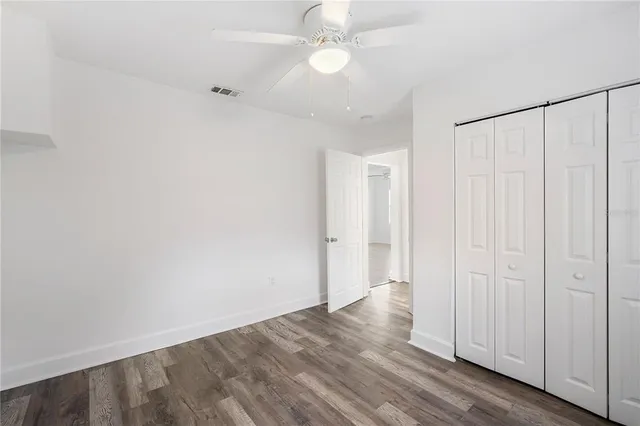 an empty room with wooden floor fan and windows