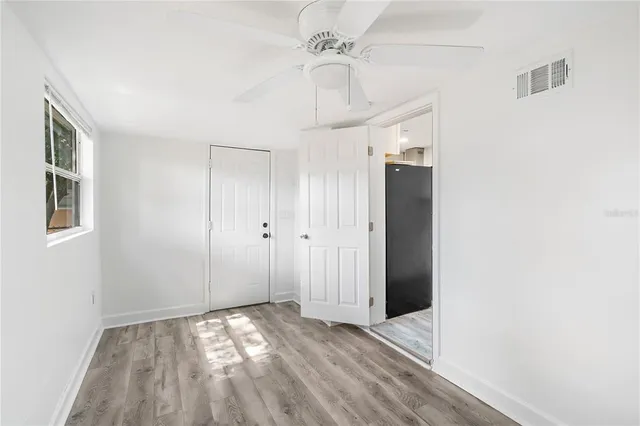 a view of an empty room with window and wooden floor