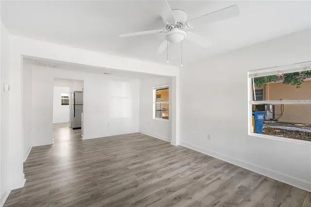 a view of a big room with wooden floor a ceiling fan and windows