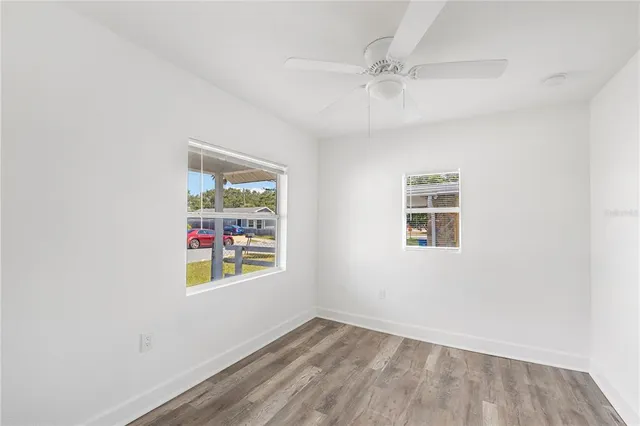 an empty room with windows and fan