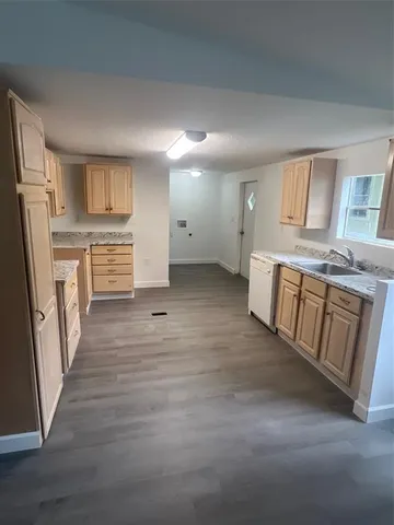 an empty room with wooden floor and stainless steel appliances