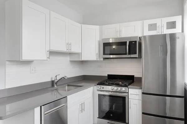 a kitchen with stainless steel appliances granite countertop white cabinets granite counter tops and a stove top oven