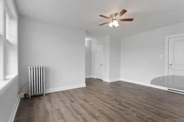 an empty room with wooden floor and ceiling fan