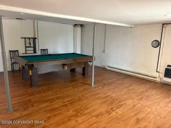 a room with wooden floor pool table and windows