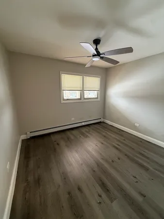 an empty room with wooden floor fan and windows