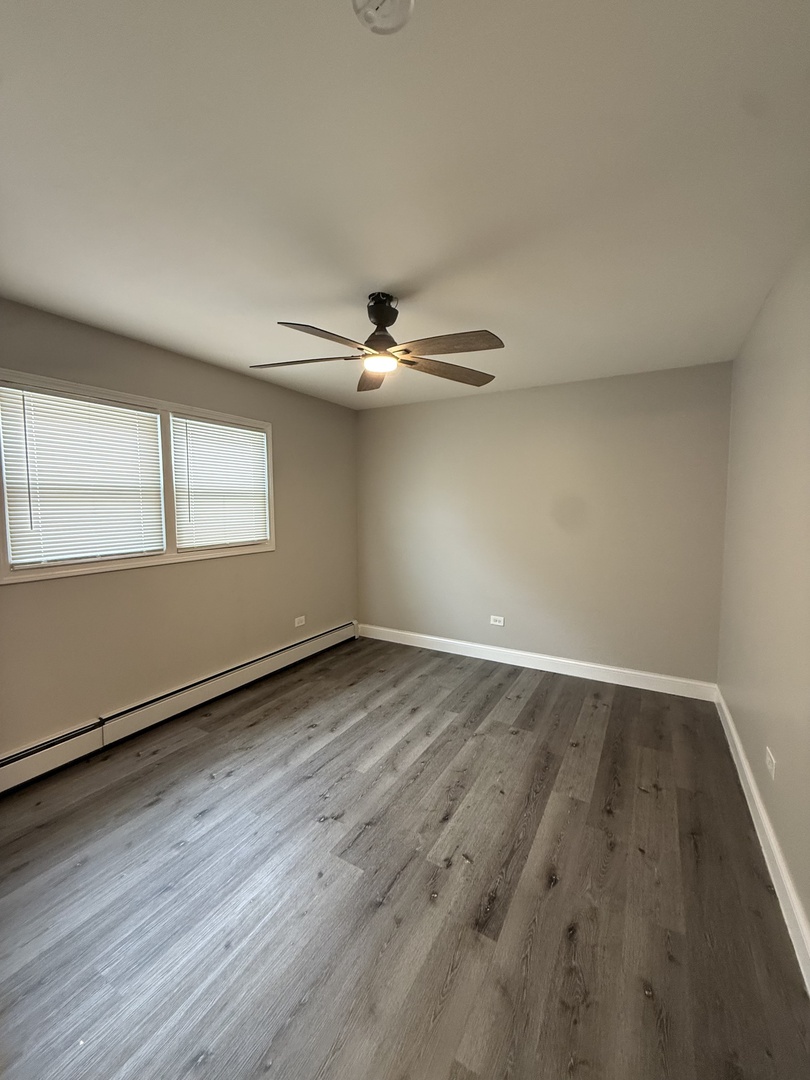 14421 South Ravinia Avenue, Unit 1S Orland Park, IL 60462 - Photo 7 of 9 an empty room with wooden floor fan and windows