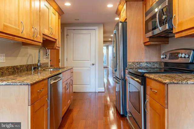a kitchen with stainless steel appliances granite countertop a refrigerator a stove and a wooden floors