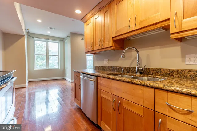 a kitchen with granite countertop wooden cabinets a sink and dishwasher