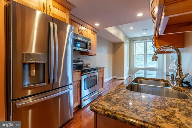 a kitchen with stainless steel appliances granite countertop a sink a stove and a refrigerator
