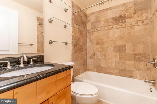 a bathroom with a granite countertop sink mirror toilet and bathtub