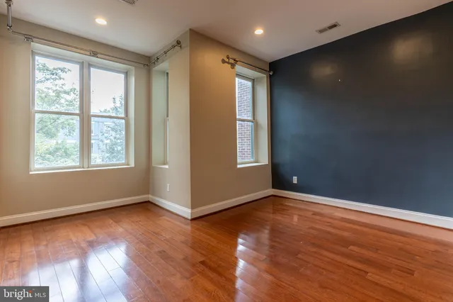 an empty room with wooden floor and windows