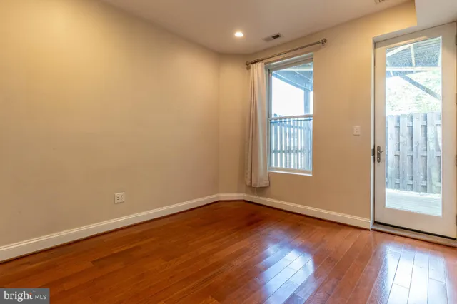 a view of empty room with wooden floor and fan