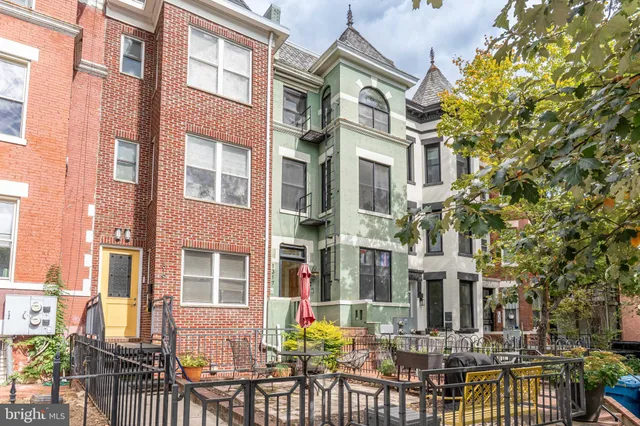 a front view of a building with balcony and outdoor seating