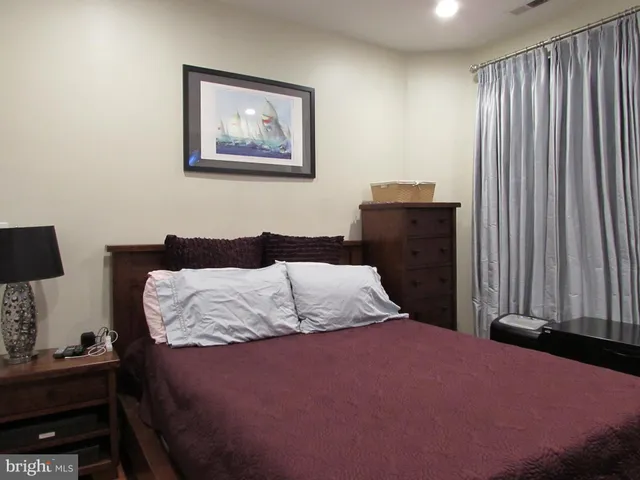 a bedroom with a bed and a lamp on dresser