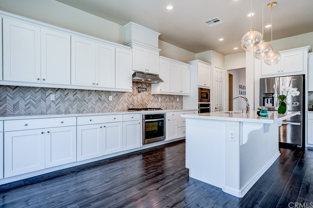 12370 Alamo Drive Rancho Cucamonga, CA 91739 - Photo 14 of 47 a kitchen with stainless steel appliances granite countertop a stove top oven a sink dishwasher and white cabinets with wooden floor