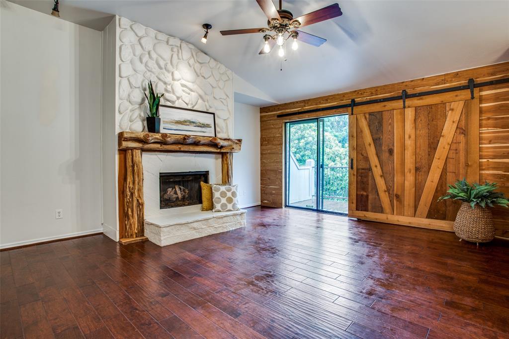 a view of an empty room with wooden floor fireplace and a window
