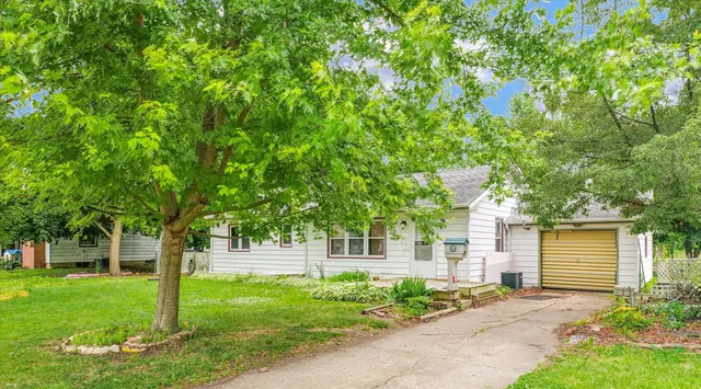 a front view of a house with a garden and tree