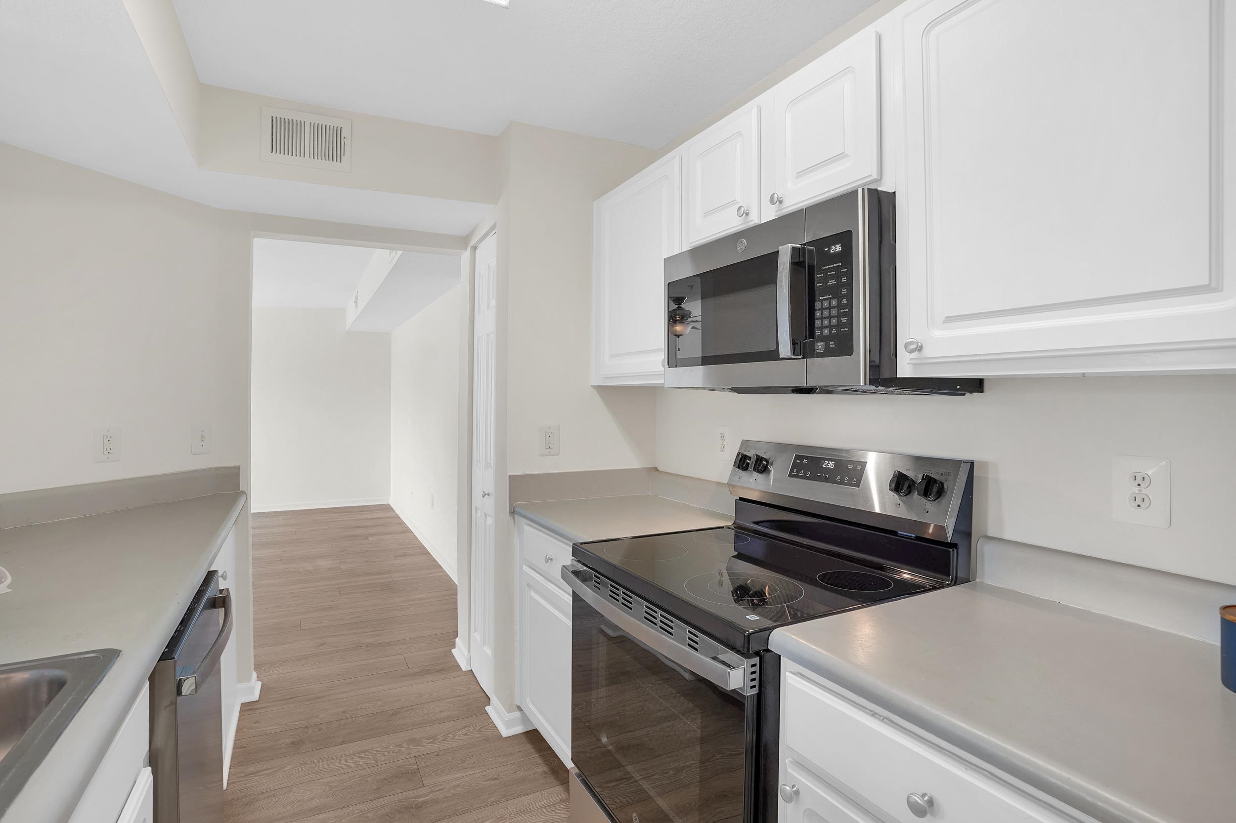 204 16th Street, Unit G St. Augustine Beach, FL 32080 - Photo 18 of 31 a kitchen with granite countertop cabinets stainless steel appliances and wooden floor