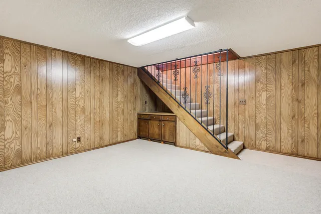 an empty room with a chandelier fan and windows