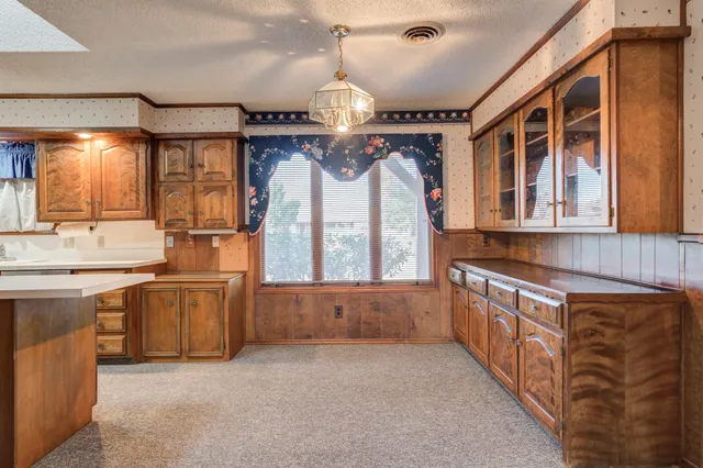 a kitchen with stainless steel appliances granite countertop a refrigerator a sink dishwasher a stove and white countertops with wooden floor