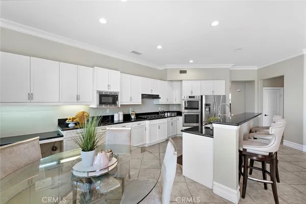 a kitchen with stainless steel appliances kitchen island granite countertop a stove a sink a refrigerator a dining table and chairs