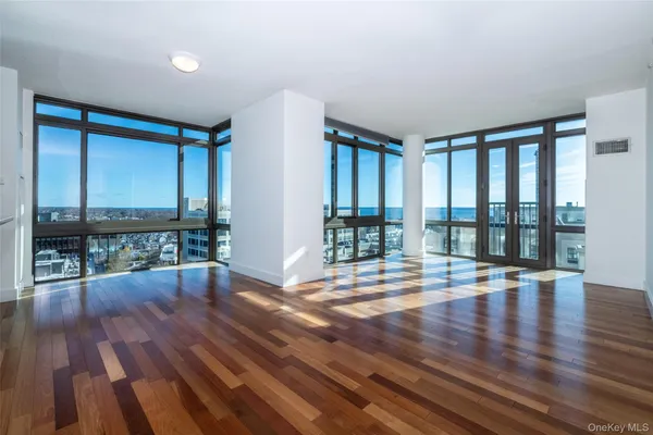 a view of empty room with wooden floor and floor to ceiling window