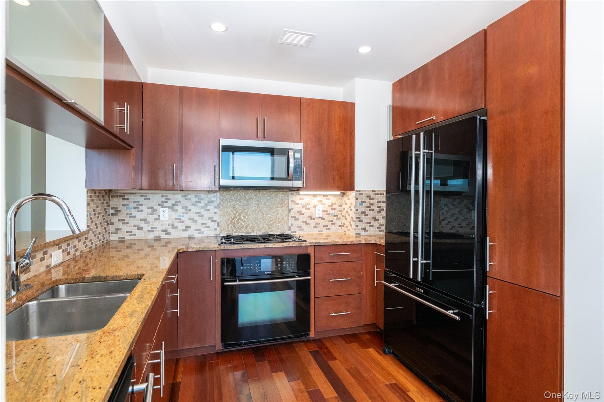 175 Huguenot Street, Unit 1402 New Rochelle, NY 10801 - Photo 8 of 24 Kitchen with light stone countertops, black appliances, dark wood-type flooring, tasteful backsplash, and recessed lighting