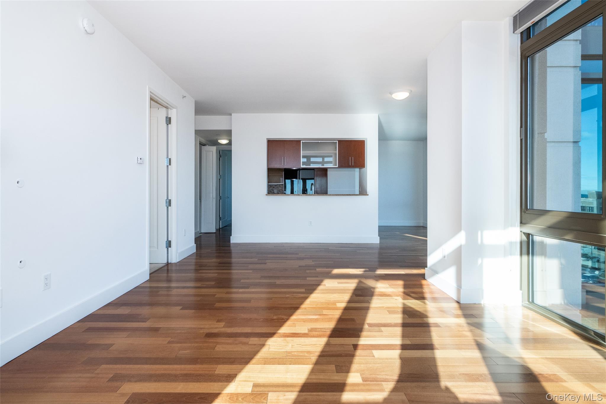175 Huguenot Street, Unit 1402 New Rochelle, NY 10801 - Photo 10 of 24 Unfurnished living room with dark wood finished floors and baseboards
