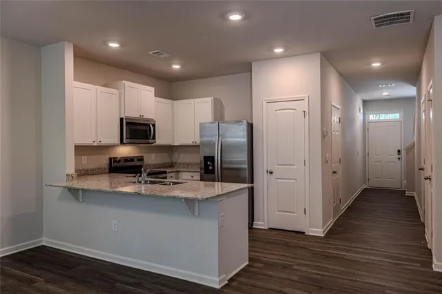 a kitchen with kitchen island granite countertop a sink cabinets and stainless steel appliances