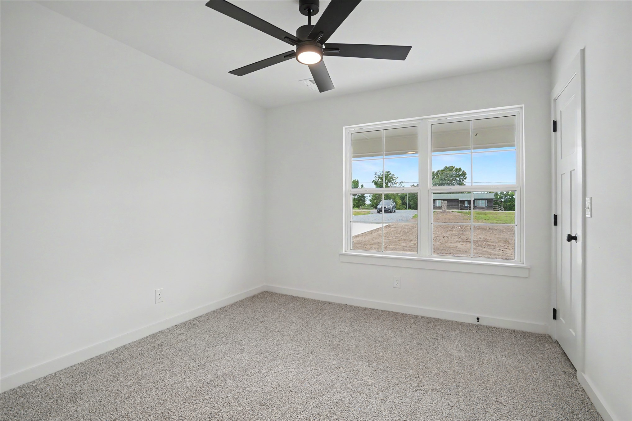 1445 South 4260th Road Chelsea, OK 74016 - Photo 22 of 33 Interior room featuring a large window, neutral carpet, white walls, and a contemporary ceiling fan with integrated lighting